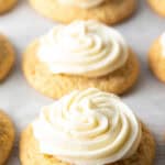 Several honey butter cornbread cookies on a white background, each topped with piped frosting.