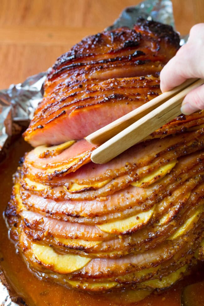 Choosing the slices of ham with the apples with a pair of tongs. 