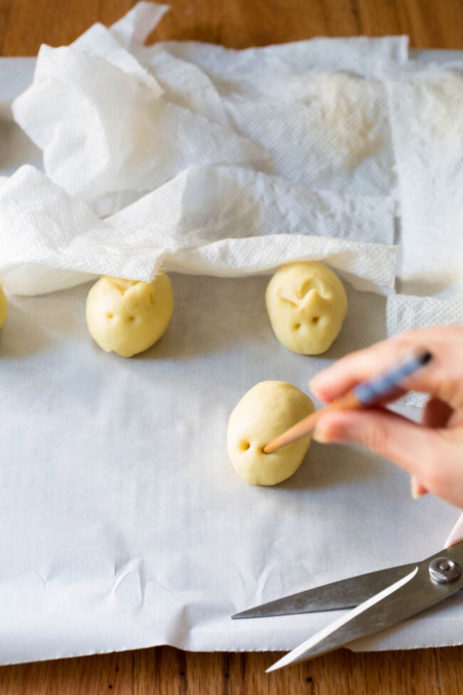 Hand holding a chopstick to make eyes in the dough. 