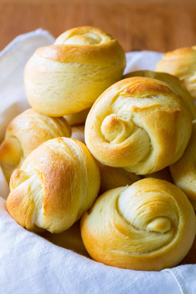 Dinner rolls stacked on top of each other in a bread basket. 