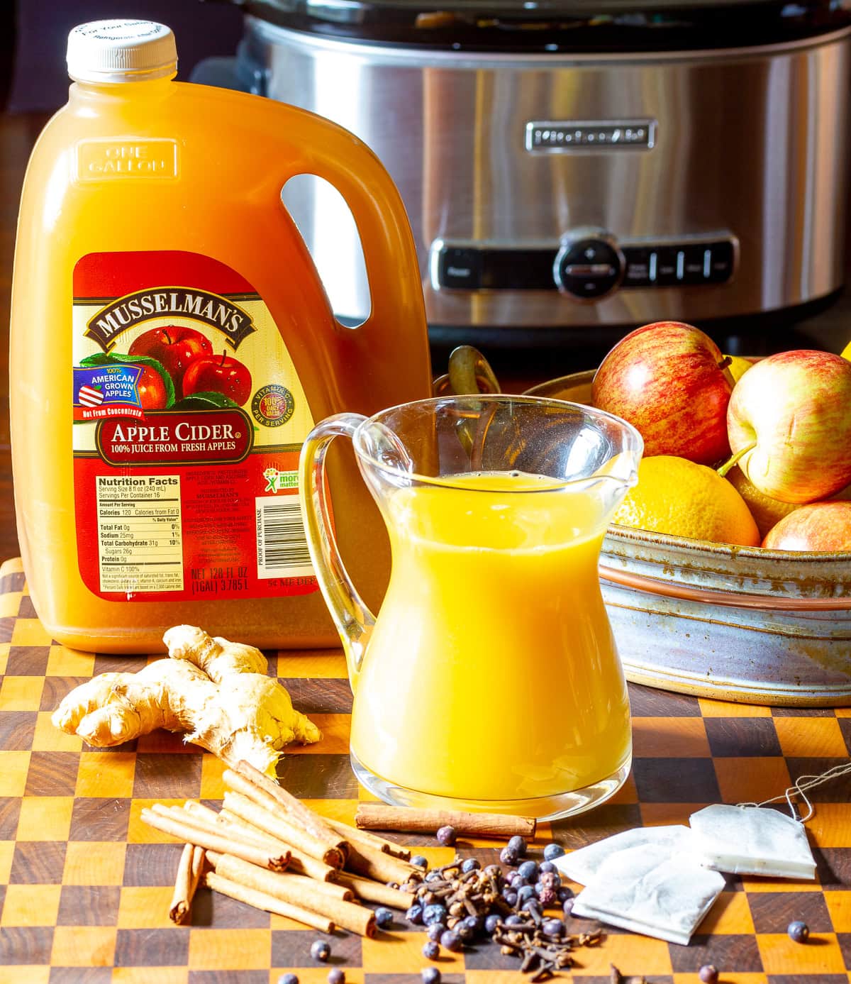 Ingredients needed to make wassail recipe with a crockpot in the background. 