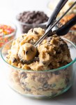 Glass cup of cookie dough, small scoop showing to camera.