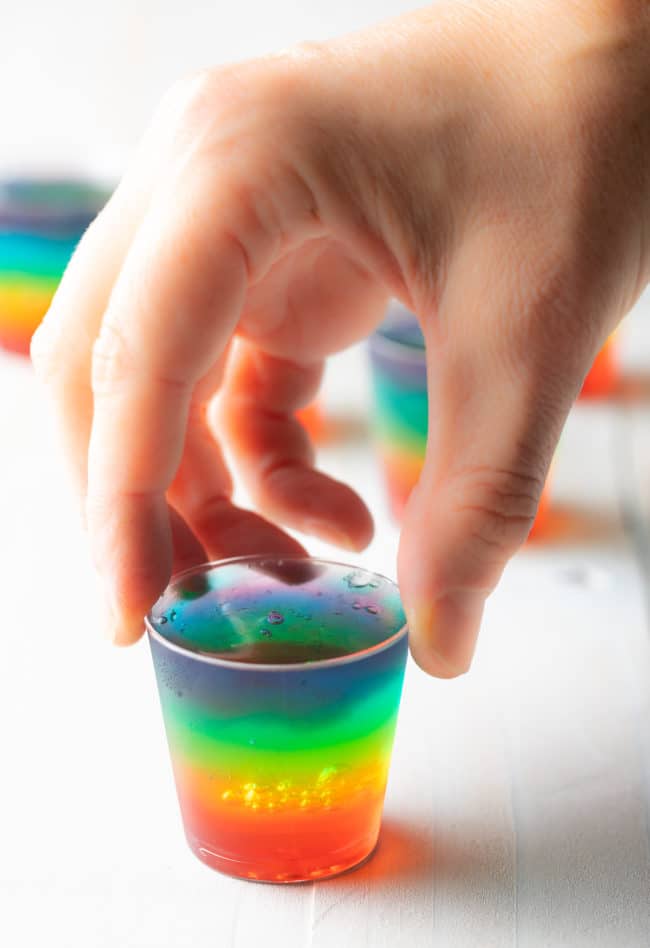 How to Make Jello Shots - hand holding rainbow jello shot cup