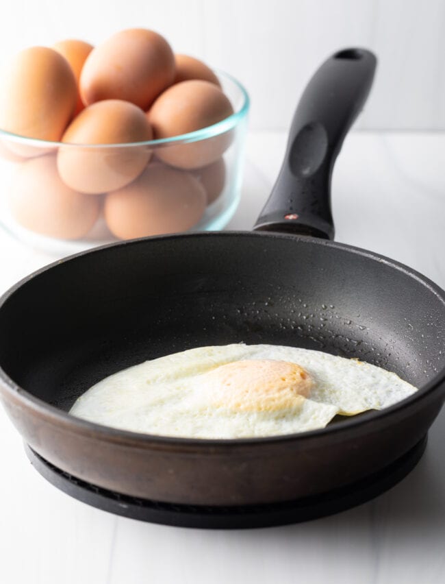 Soft fried egg over easy in a black nonstick skillet.