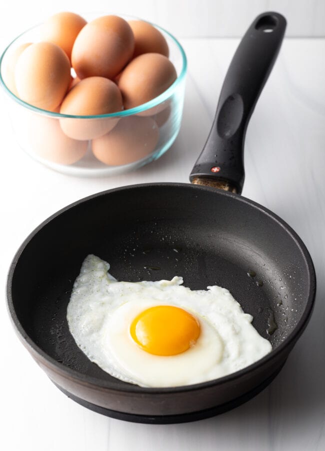 Sunny side up egg cooking in a black skillet.