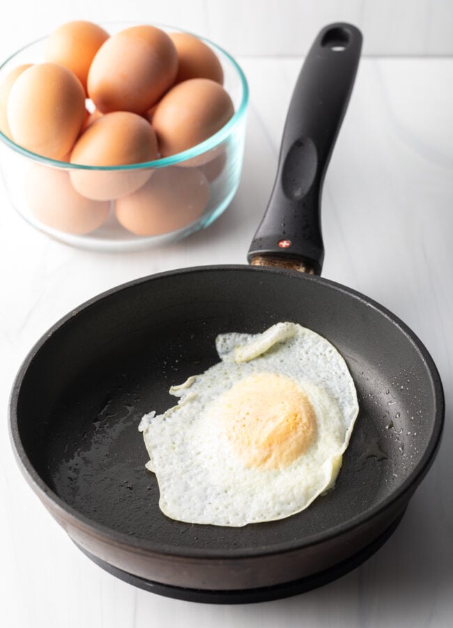 Soft fried egg over easy in a black nonstick skillet.