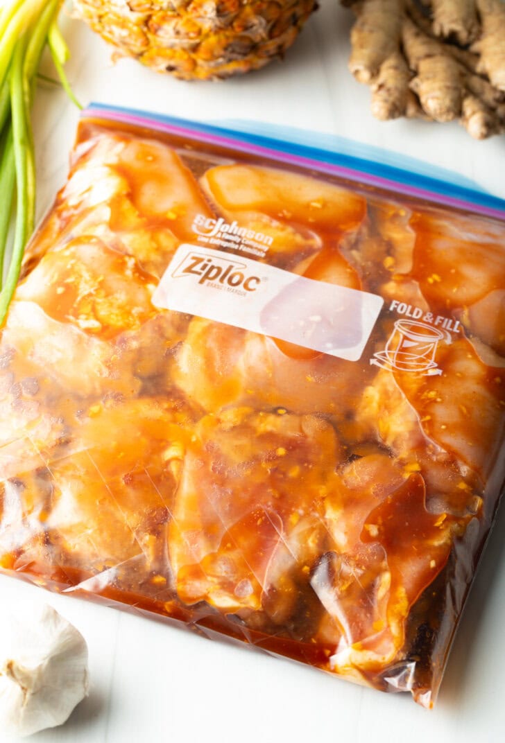 Raw chicken pieces in a plastic ziploc bag with Hawaiian chicken pineapple marinade.