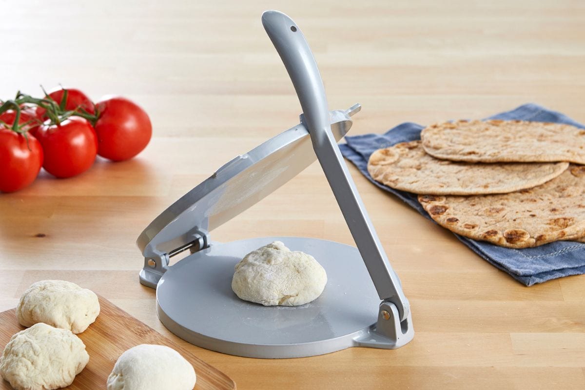 Imusa tortillla press with tortilla dough in the middle. 