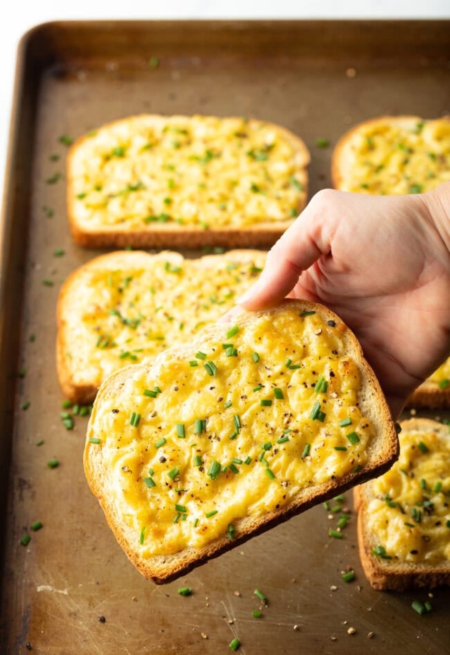 Hand holding piece of cheese toastie to camera.