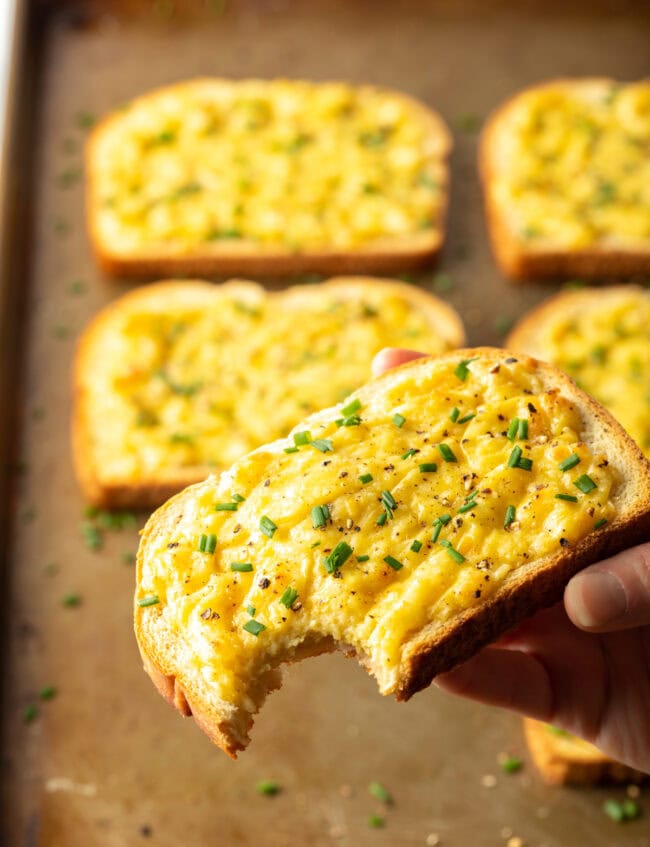 Hand holding piece of Irish cheese toastie with bite taken out.