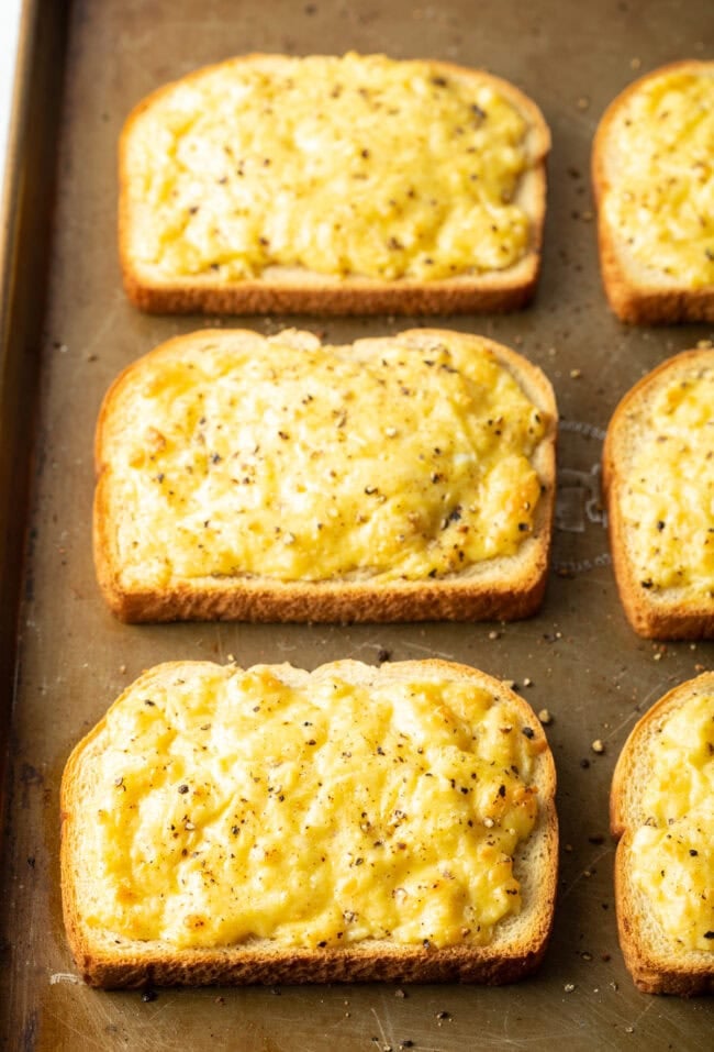 Baked cheese toasties on baking sheet.