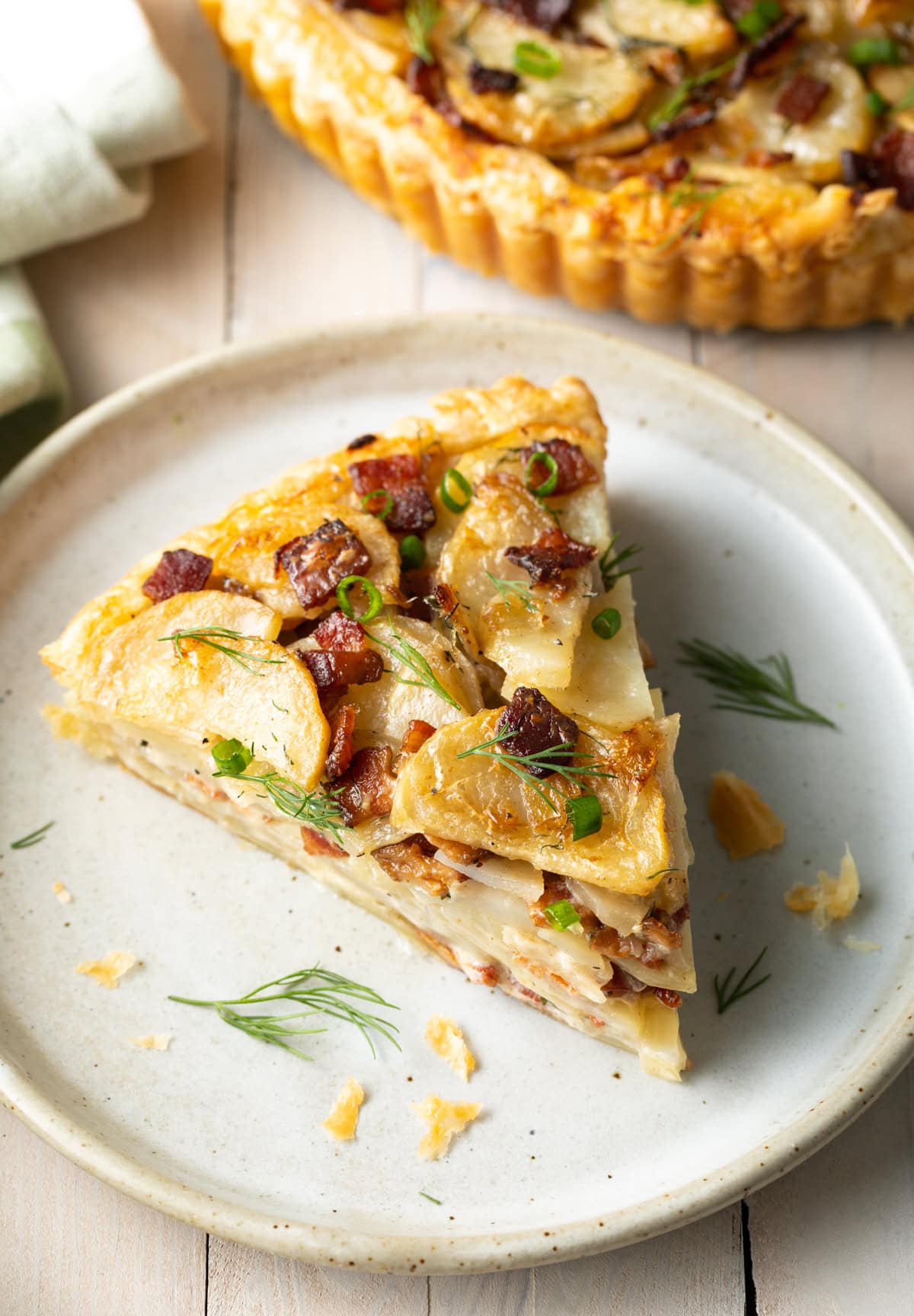 Slice of potato pie on a plate garnished with dill. 