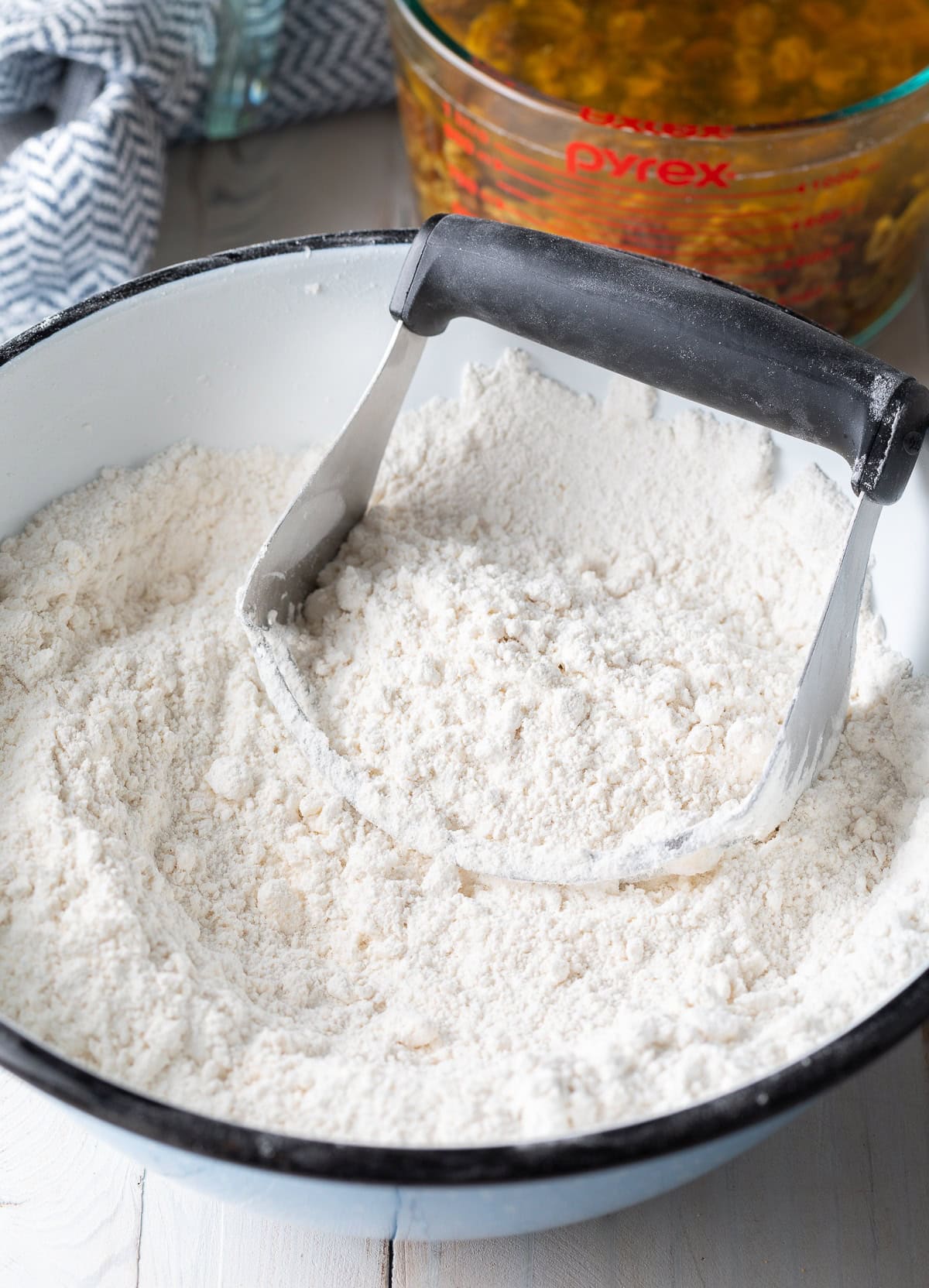 Flour in a white mixing bowl with a pastry cutter. 