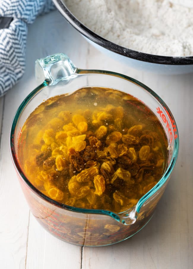 Raisins soaking in water in a glass measuring cup. 