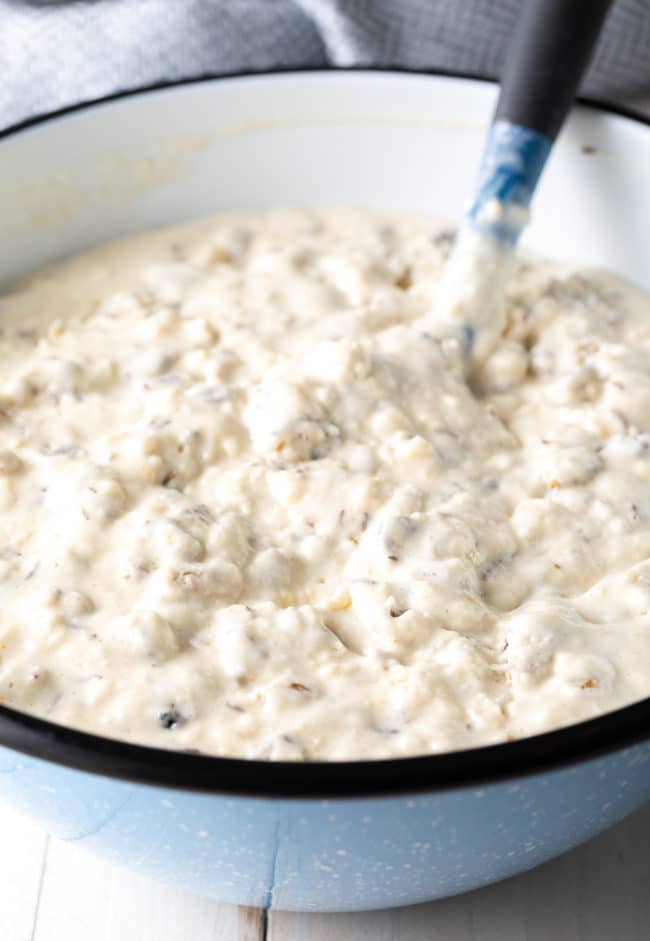 Soda bread batter in a white mixing bowl with a rubber spatula. 