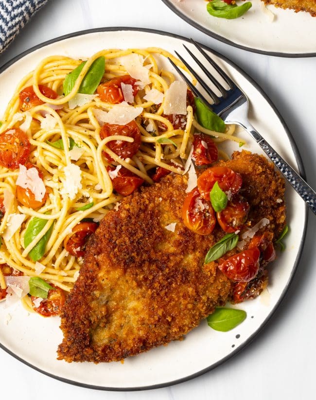 overhead view of finished plate with crunchy Panko Italian breasts cut thin, on a plate with spaghetti and cherry tomato sauce on the side