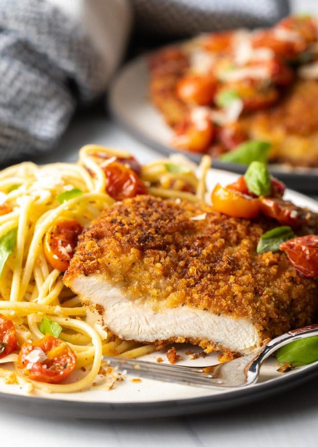 cut breast showing meat inside, on a plate with fork and pasta