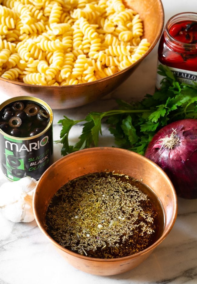 Pasta salad ingredients with dressing in a bowl. 