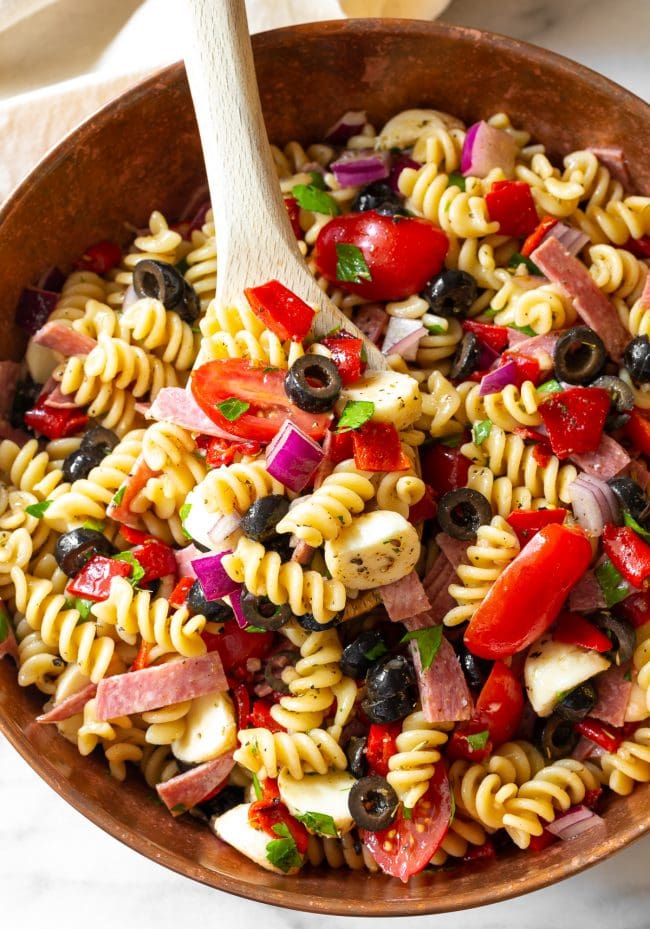 Italian pasta salad in a bowl with a wooden spoon. 