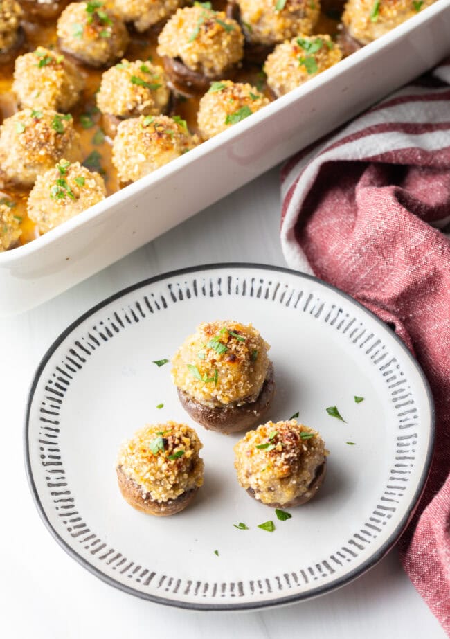 Three mushrooms stuffed with Italian sausage and cheese on a white plate.