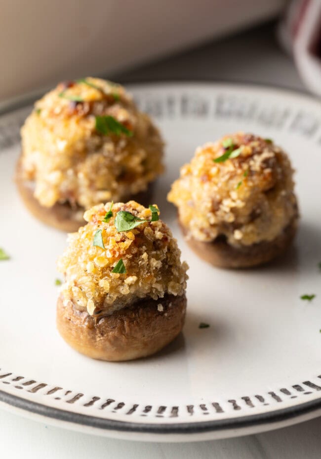 Three mushrooms stuffed with Italian sausage and cheese on a white plate.