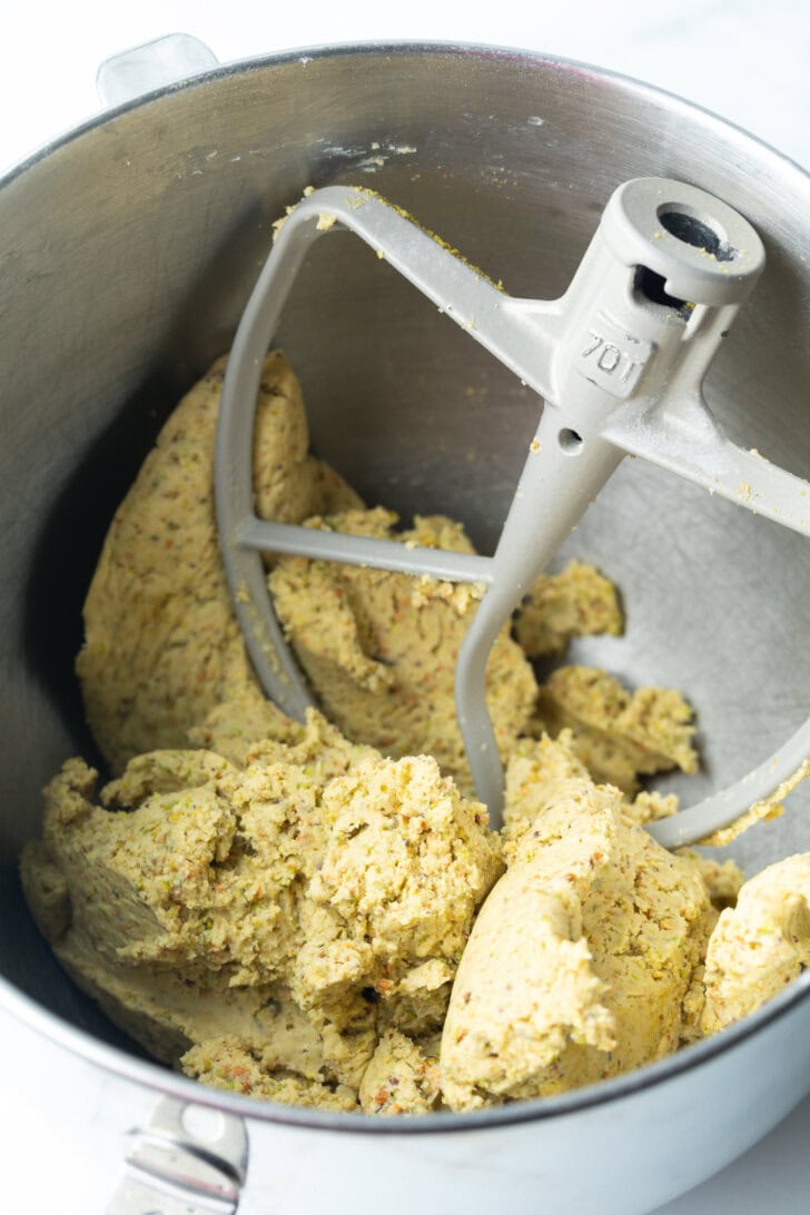 Cookie dough in a metal mixing bowl, with mixer paddle in the bowl.