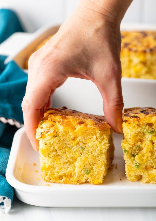 Hand grabbing this cornbread recipe with jalapenos and cheese