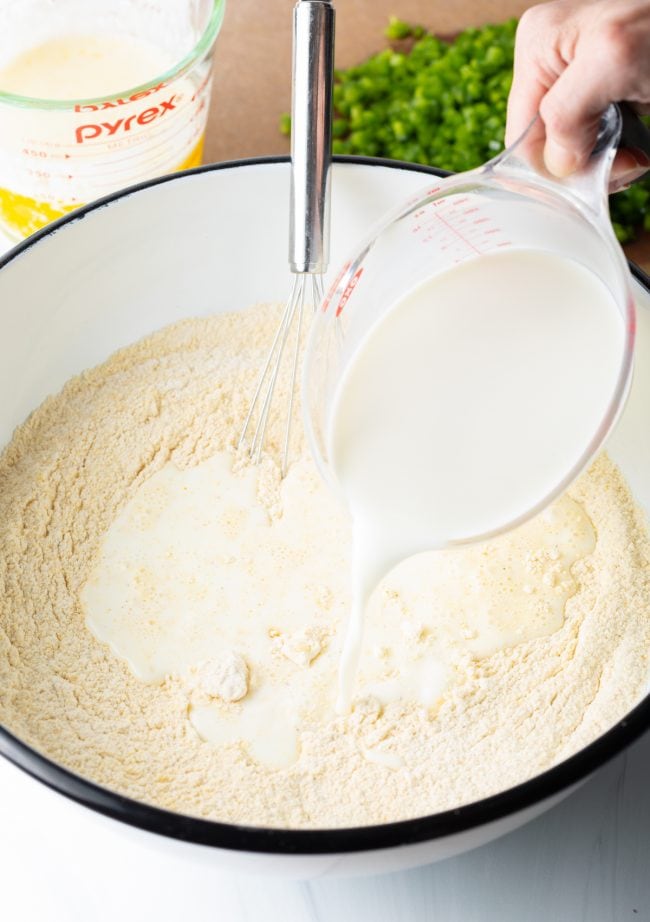 pouring buttermilk into a bowl with baking mix about to whisk it up