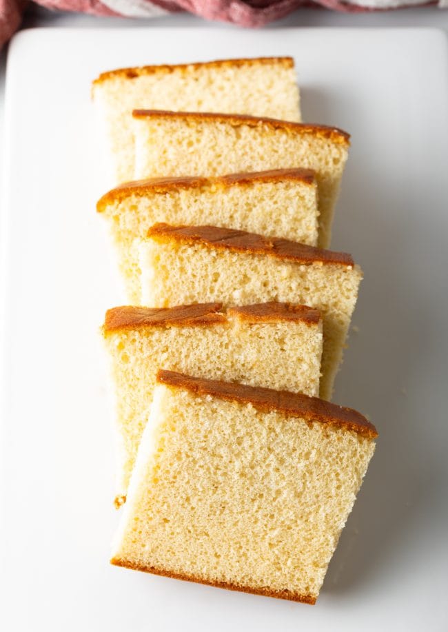 Slices of Japanese Sponge Cake lined up on a white plate.