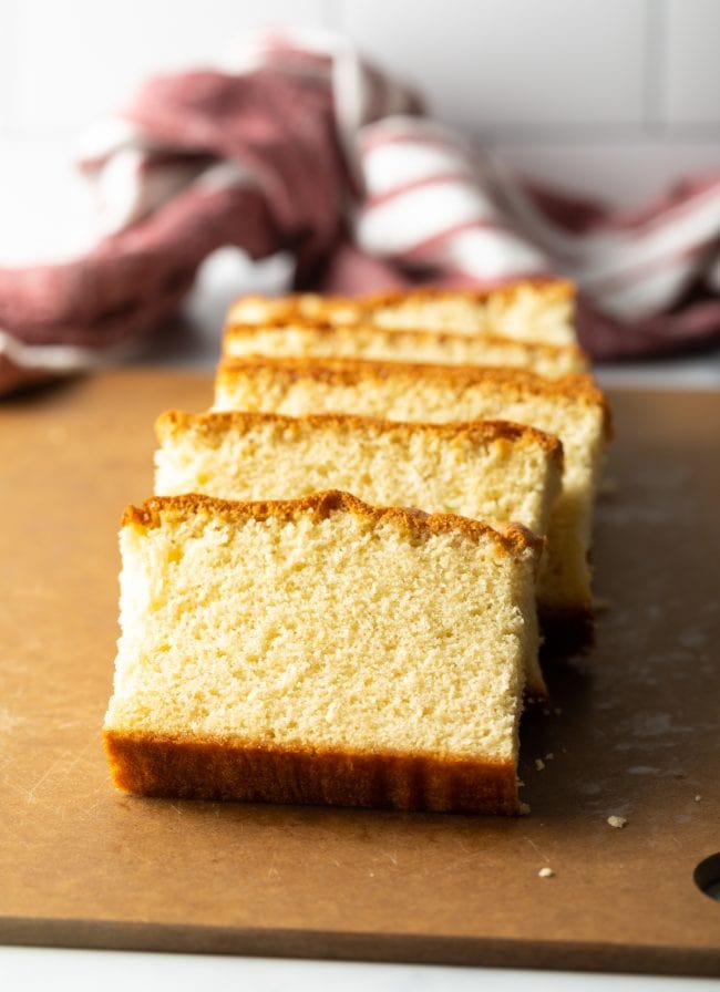 slices of Japanese sponge cake on a brown cutting board, all leaning on each other