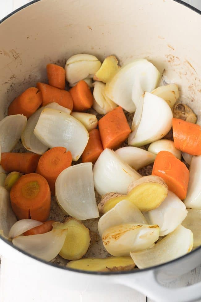 Carrots, onions, garlic and ginger being sautéed in a large stock pot. 