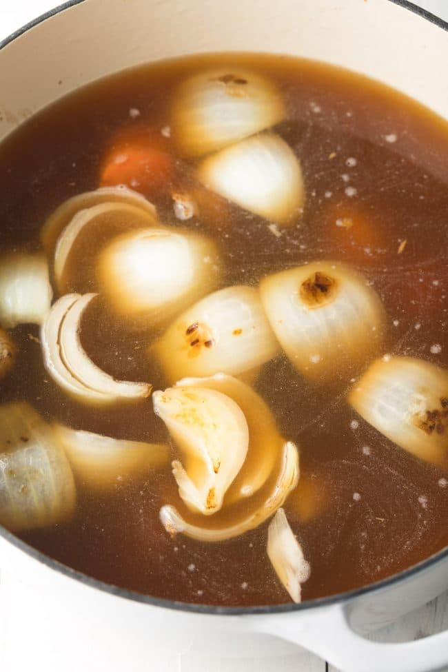 Soup simmering in a large pot with big pieces of veggies in it. 