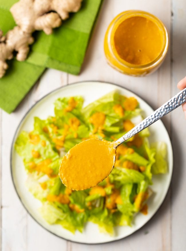 Ginger Salad dressing in a spoon with salad in the background. 