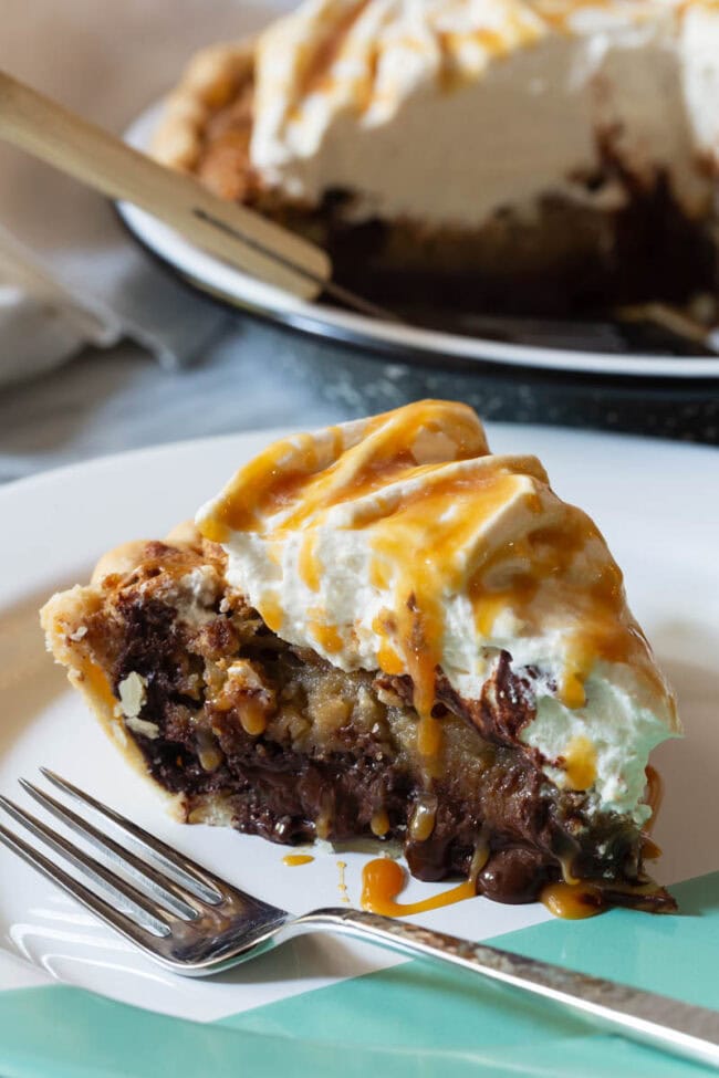 A slice of chocolate pecan pie on a white plate with a fork.