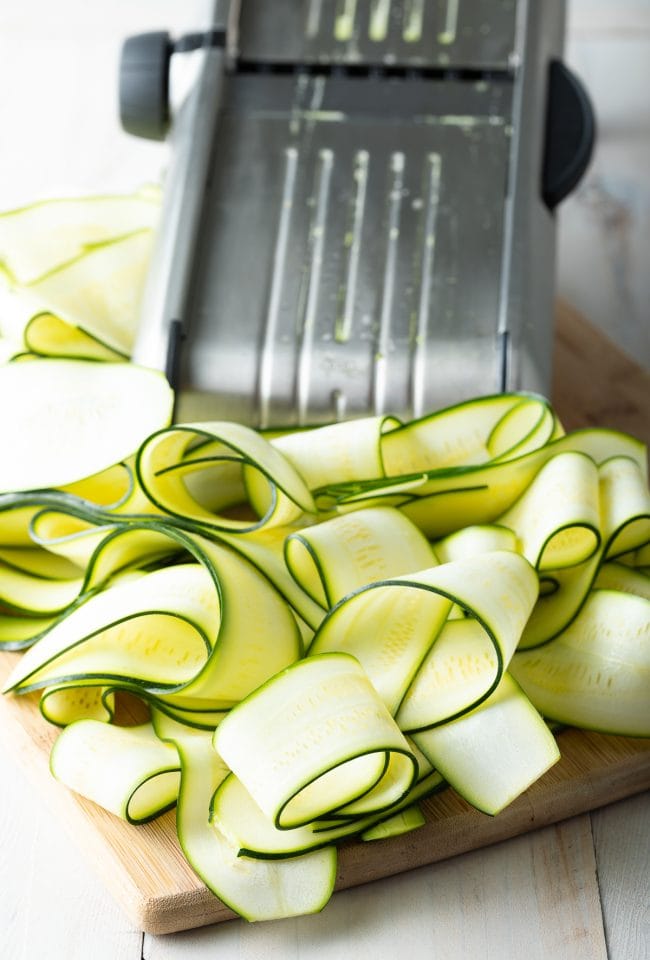 slices of zucchini next to a mandoline slicer. 