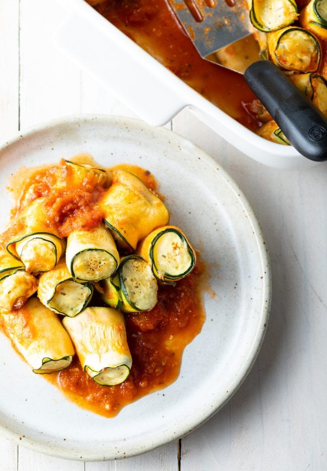 plate of low carb lasagna roll ups next to the baking dish full of them. 