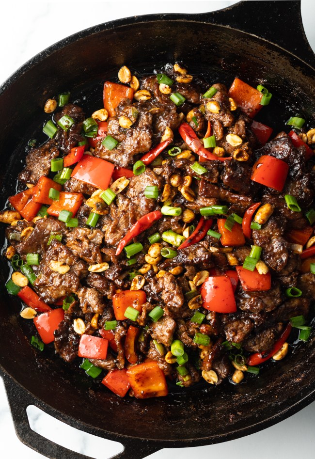 Chopped beef, red bell peppers, and scallions cooked together in a cast iron skillet.