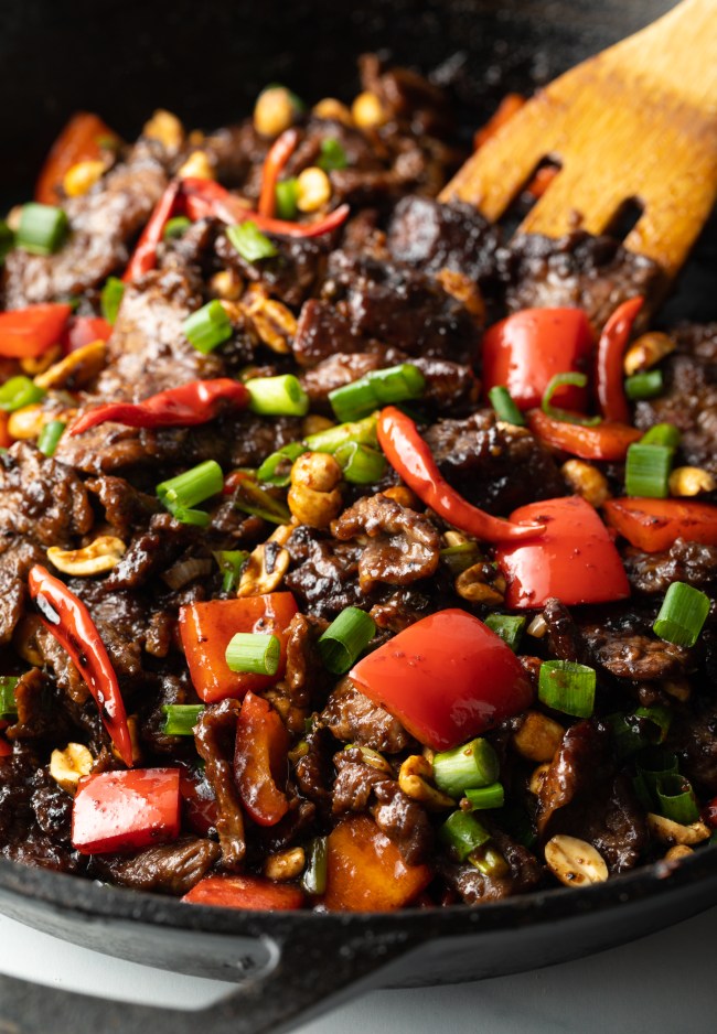 Chopped beef, red bell peppers, and scallions cooked together in a cast iron skillet.