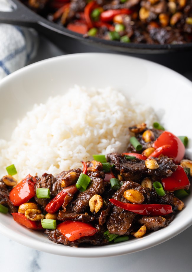 Kung pao beef stir fry serving in a white bowl with white rice.