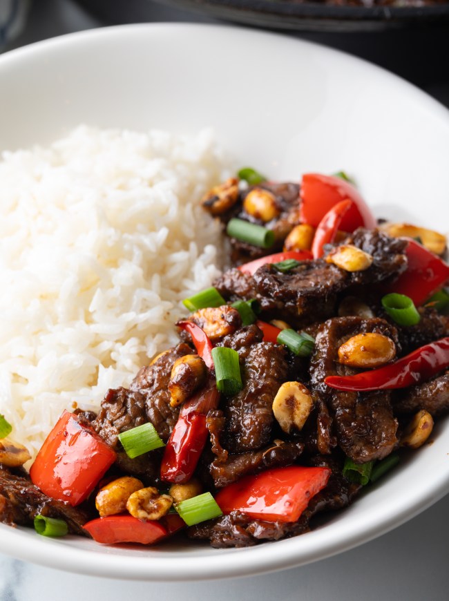 Kung pao beef stir fry serving in a white bowl with white rice.