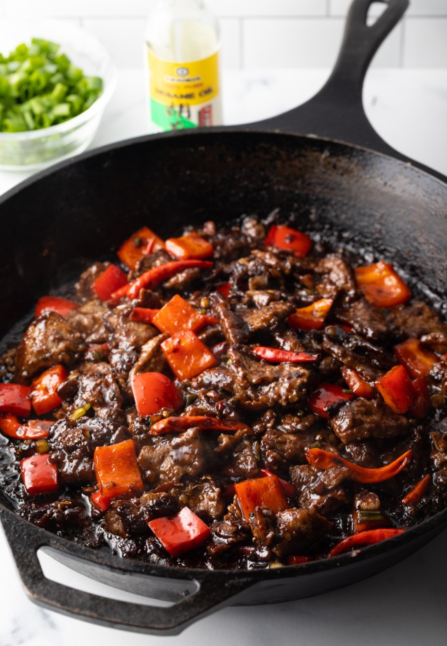 Chopped steak and bell peppers stir fried in a skillet.