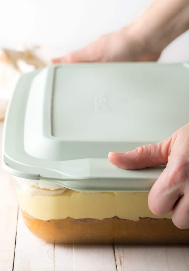 Pyrex Deep Dish with hands putting a lid on top to store. 