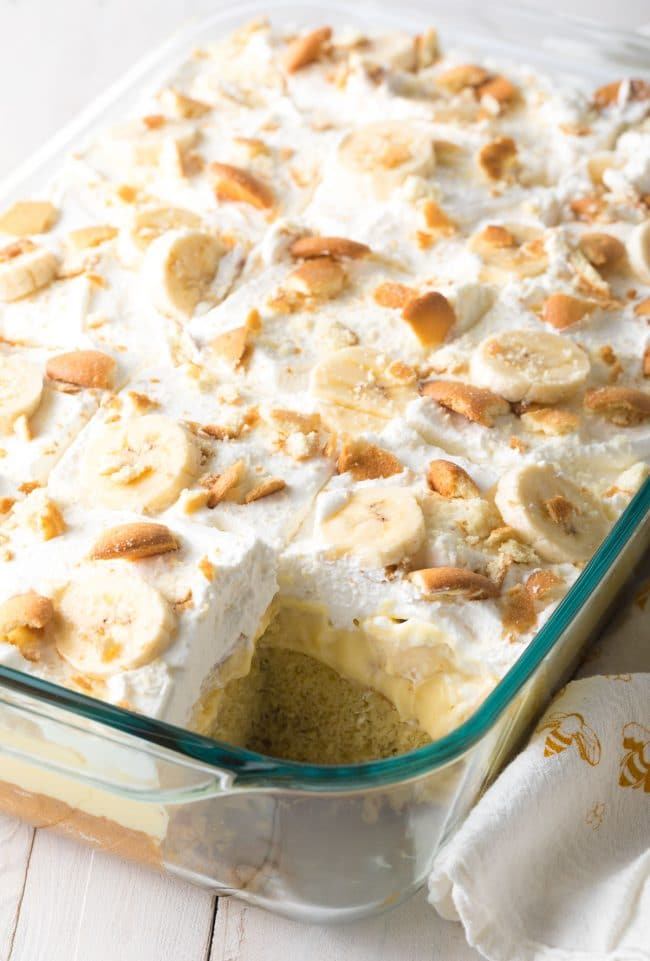 Layered banana cake in a glass baking dish with a piece missing. 