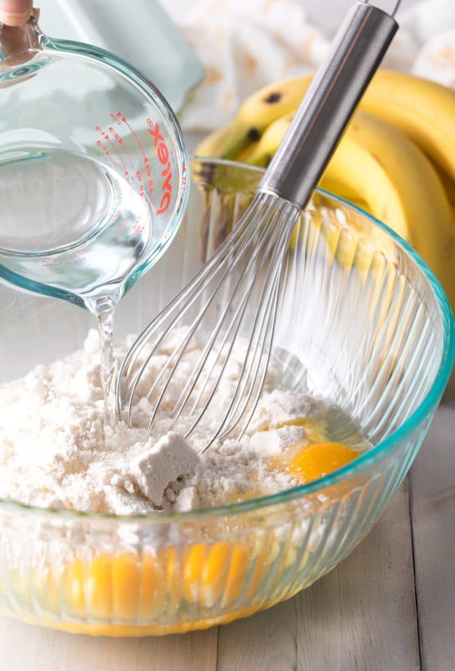 Cake batter being whisked together in a glass mixing bowl. 