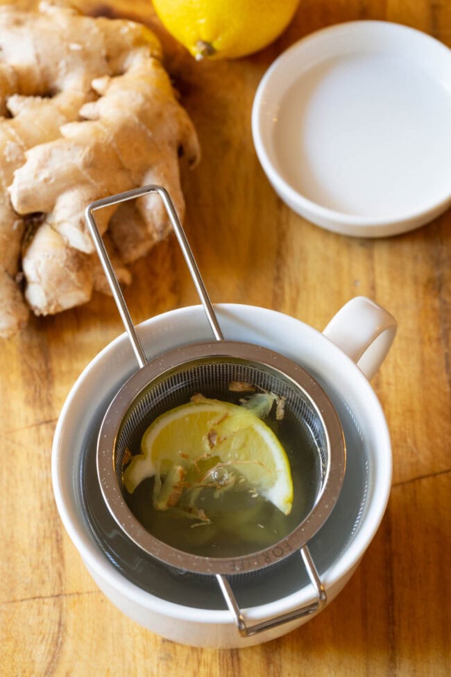 Lemon ginger detox tea in a mug with a tea infuser.