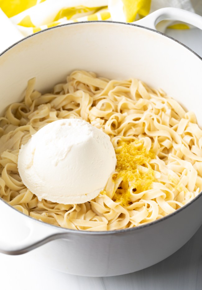 Pot with fettuccine, garlic and lemon, and large scoop of ricotta cheese on top.