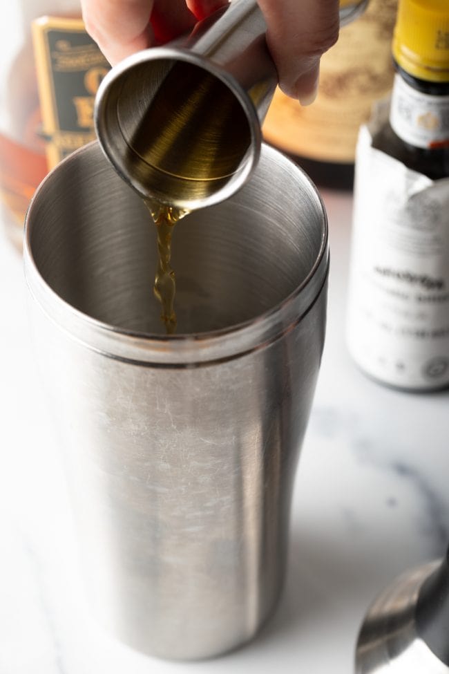 Perfect Manhattan Recipe being poured into a cocktail shaker. 