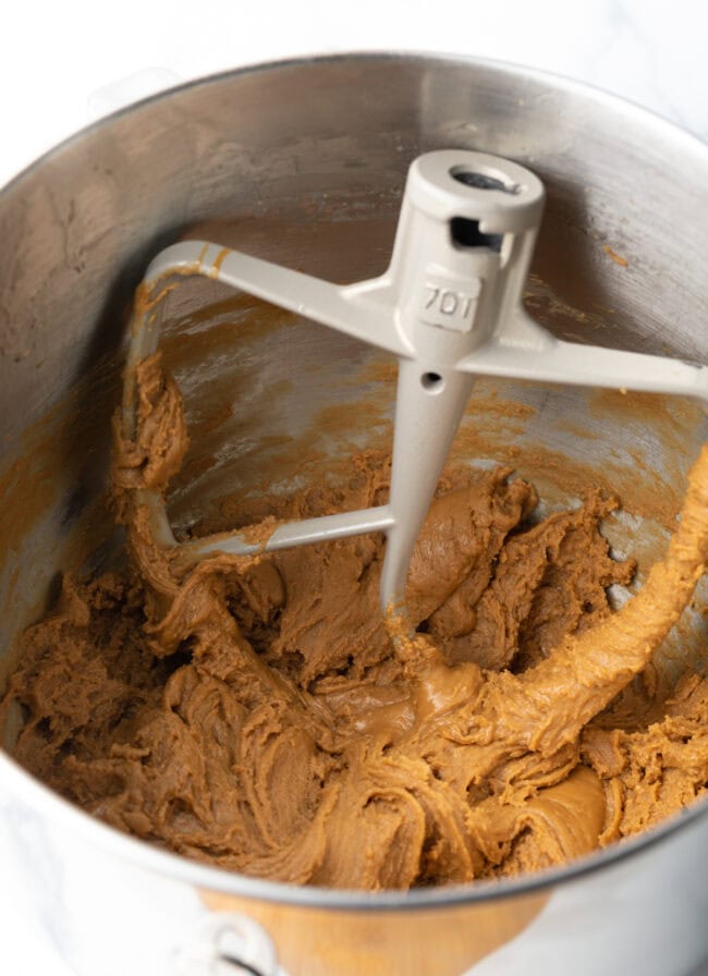 Standing mixer bowl with paddle attachment, fudge mixture in the bowl.