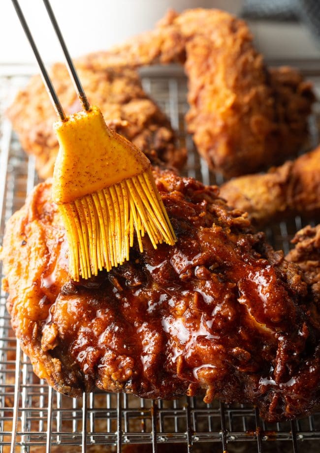 Brushing hot oil onto fried chicken.