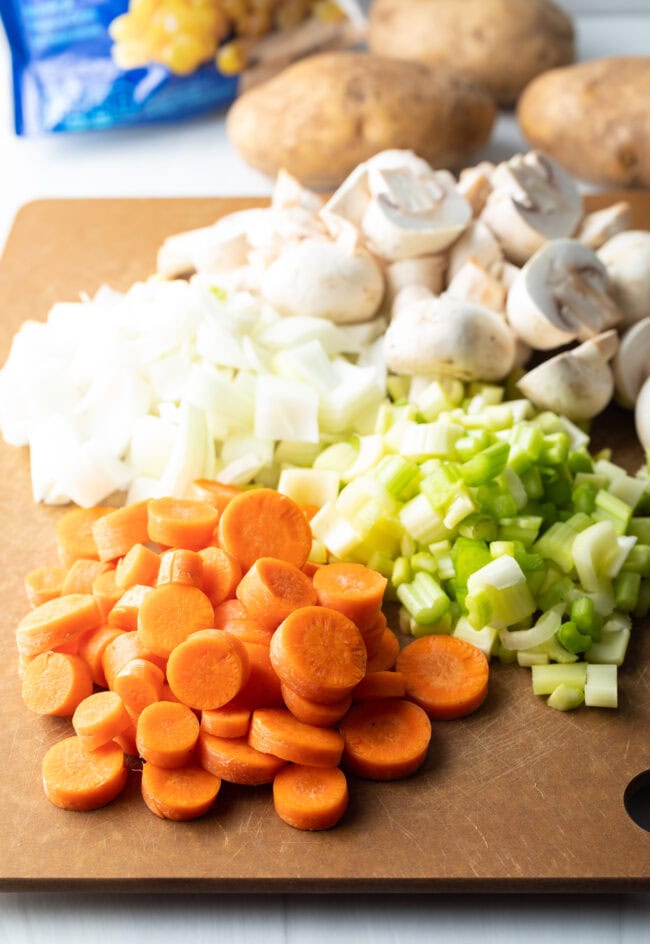 Recipe ingredients: Cutting board with chopped carrots, celery, onion, and mushrooms.